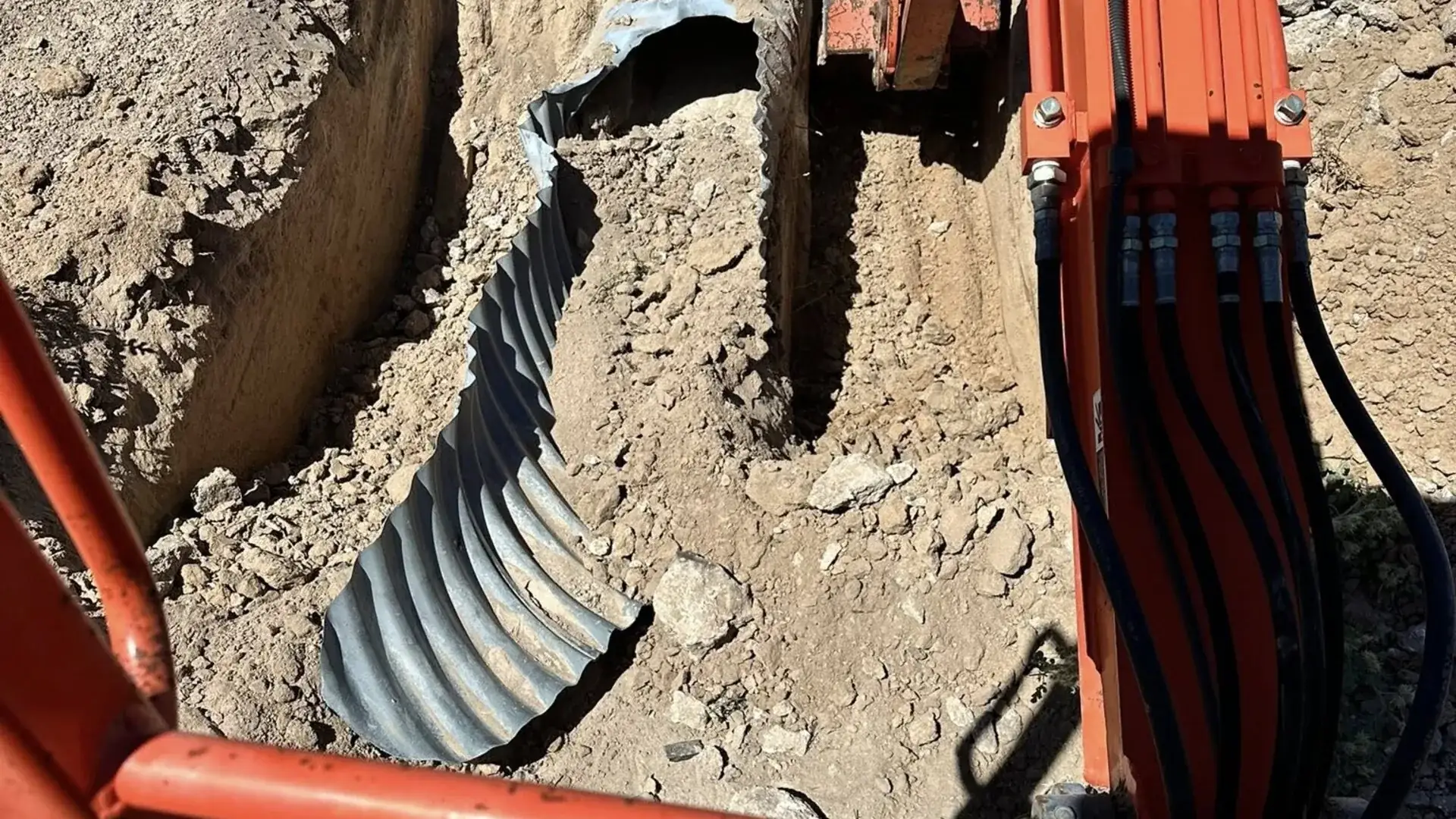 Corrugated culvert pipe being set into a freshly dug drainage trench