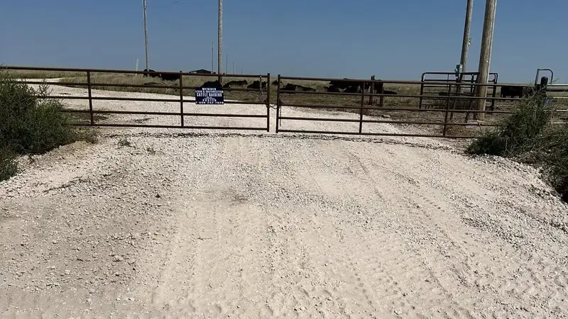 Fresh caliche ranch entrance with a metal gate