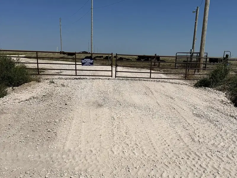 Fresh caliche ranch entrance with a metal gate