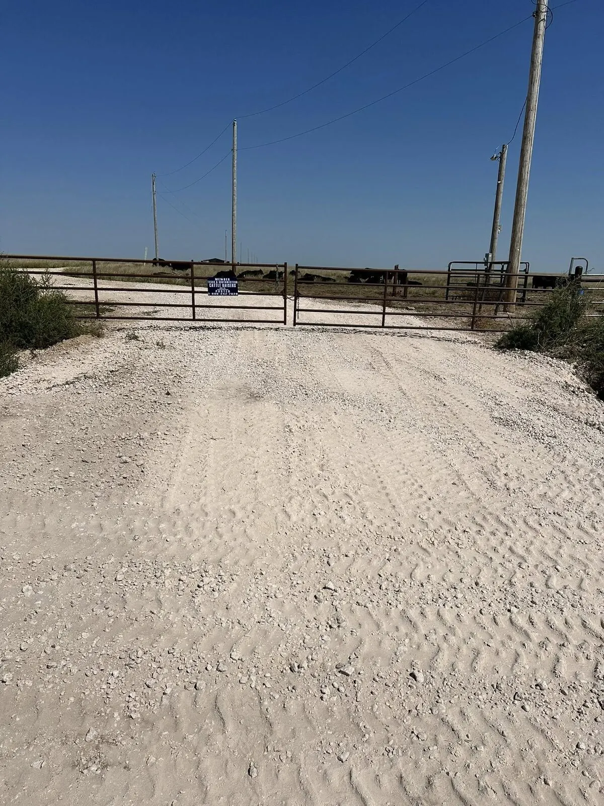 Fresh caliche ranch driveway entrance with a metal gate