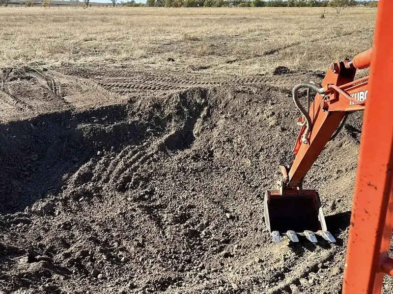 Excavator digging and grading soil on a job site