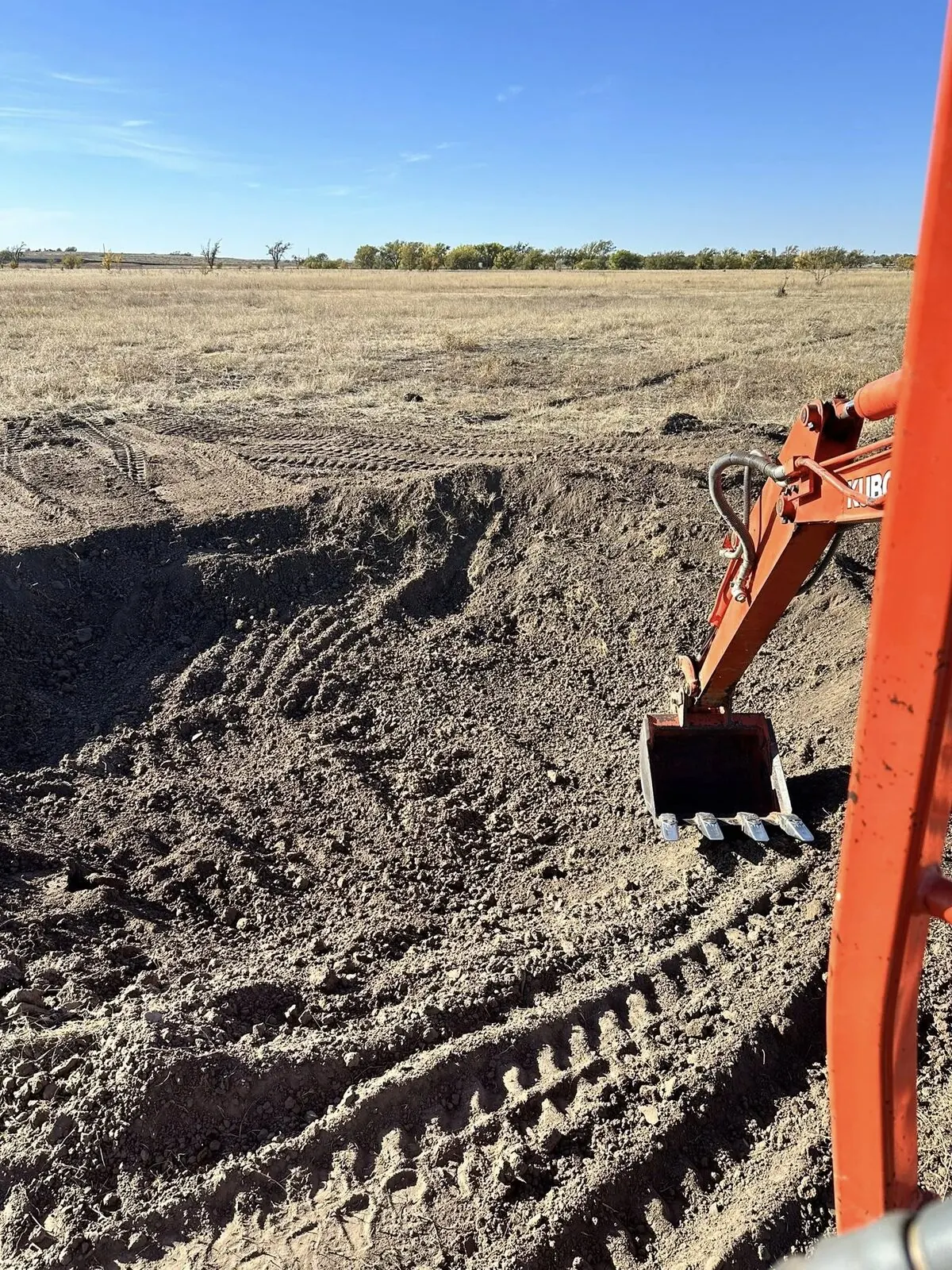 Excavator grading cleared ground