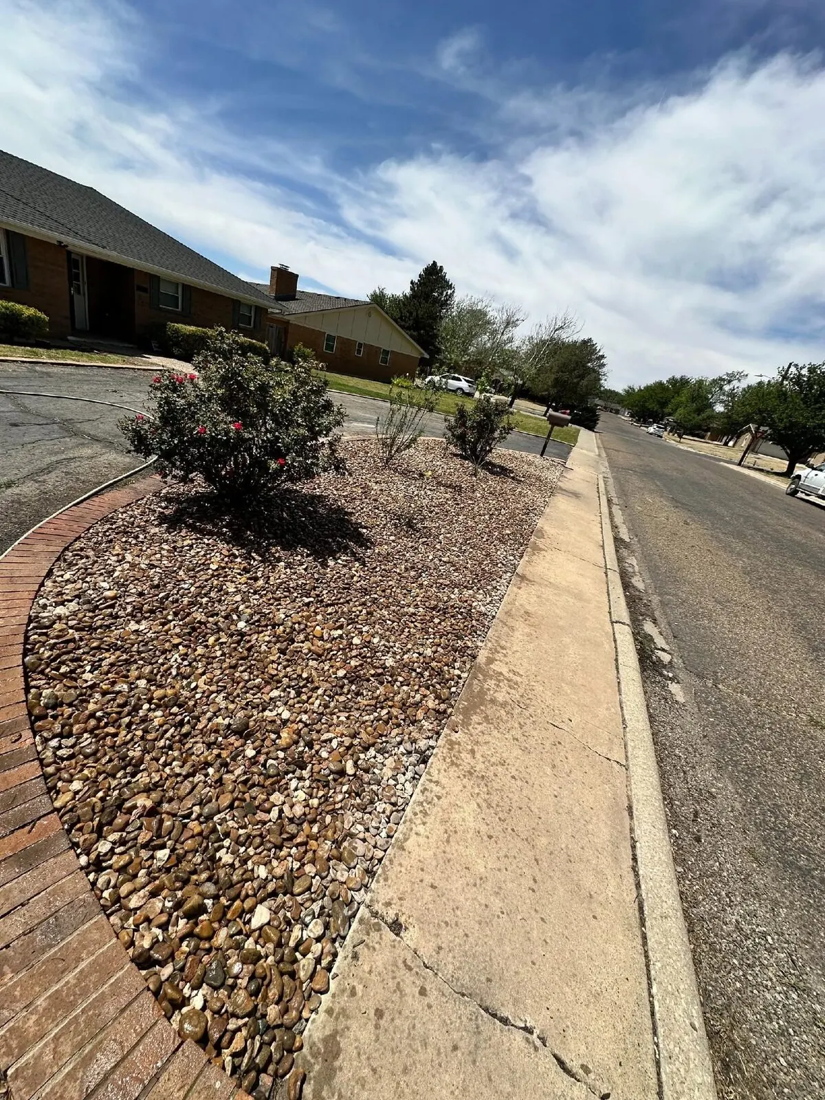 Decorative river-rock bed with brick edging along a residential drive